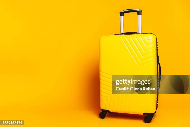 suitcase against yellow background. - luggage stockfoto's en -beelden