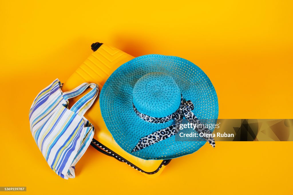 Blue hat and bag on yellow suitcase.