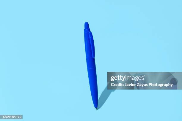 blue ballpoint pen at equilibrium on blue background - writing instrument stock photos et images de collection