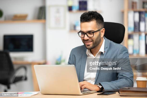オフィスで働くハンサムな若いビジネスマンの肖像画 - laptop ストックフォトと画像