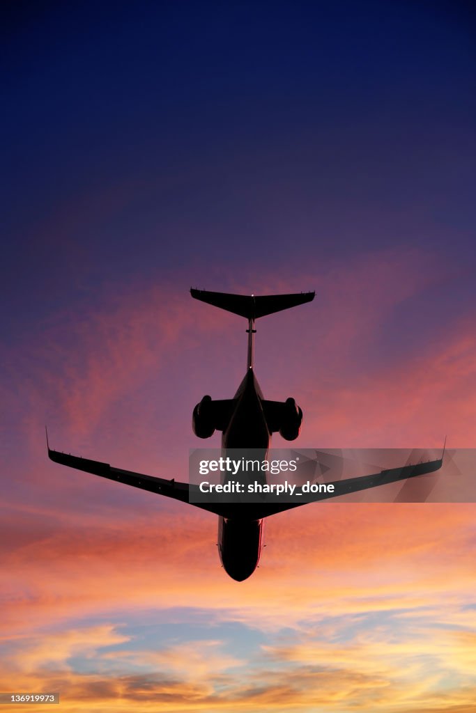 Corporate jet airplane flying at sunset