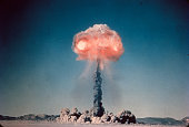 Old slide scan of atom bomb exploding in the desert with red hot fire cloud at the top