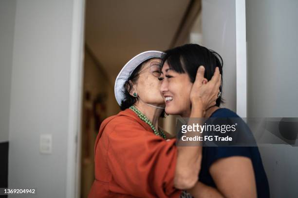 mother arriving home and being welcomed by daughter - family smiling at front door stock pictures, royalty-free photos & images