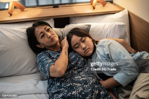 mother and daughter laying down in bed at home - lying down friends girls stock pictures, royalty-free photos & images