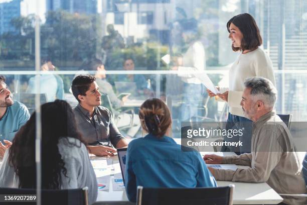 confident woman giving a presentation with a group of people. - büro gender stock pictures, royalty-free photos & images