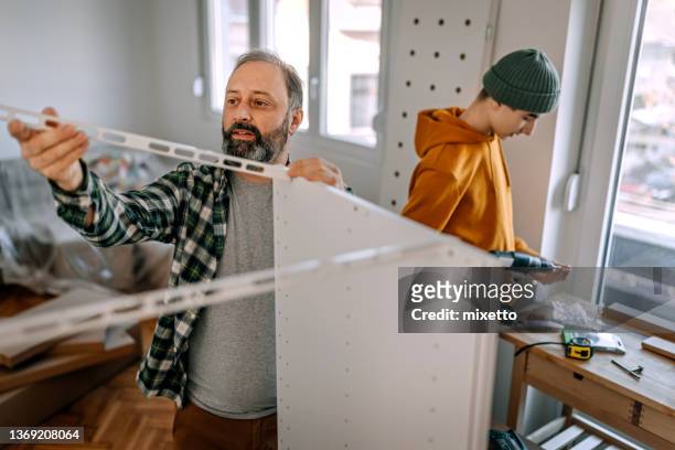 man building shelf with son - building shelves stock pictures, royalty-free photos & images
