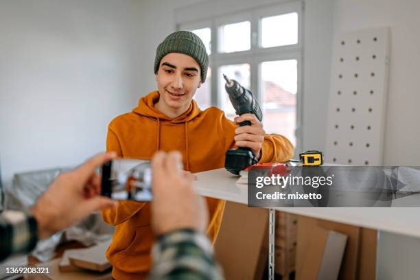 mann klickt bild von sohn hält bohrmaschine - father clicking selfie stock-fotos und bilder