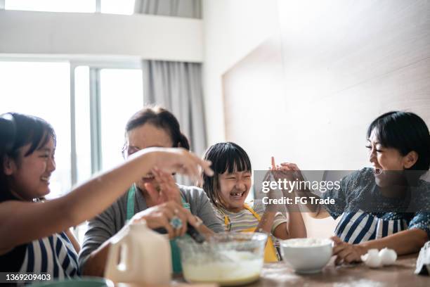 happy family making mess while preparing a cake at home - food fight stock pictures, royalty-free photos & images