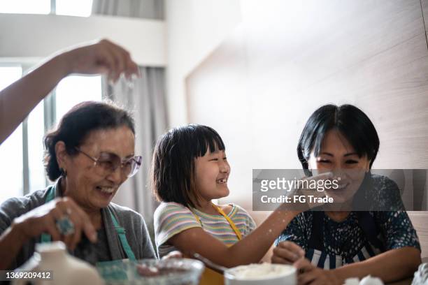 glückliche familie, die unordnung macht, während sie zu hause einen kuchen zubereitet - cooking mess stock-fotos und bilder