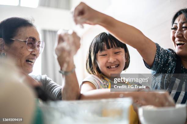 famille heureuse faisant des dégâts tout en préparant un gâteau à la maison - learning generation parent child photos et images de collection