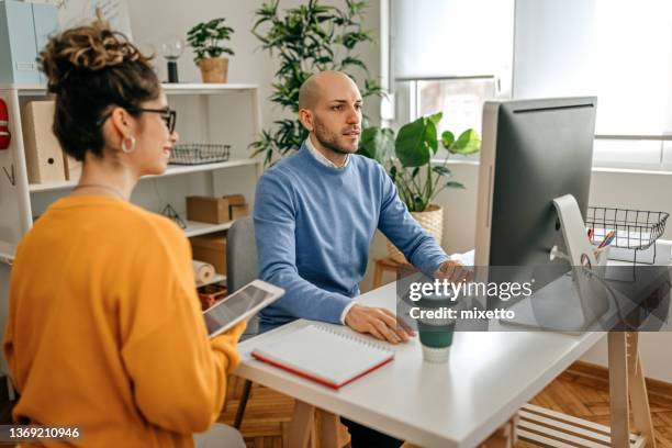 coworkers discussing at desk in office - small office stock pictures, royalty-free photos & images