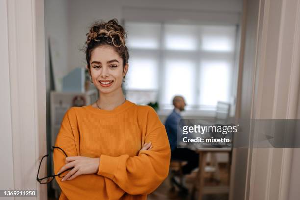 porträt einer lächelnden geschäftsfrau, die an der tür im büro steht - sweatshirt stock-fotos und bilder