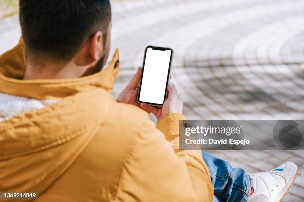 unrecognizable man sitting on a street bench while ordering food for delivery. - regarder par dessus son épaule photos et images de collection