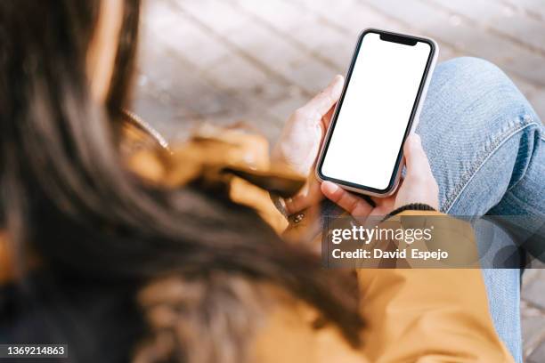 unrecognizable woman sitting on a street bench while ordering food for delivery. - over shoulder stock-fotos und bilder