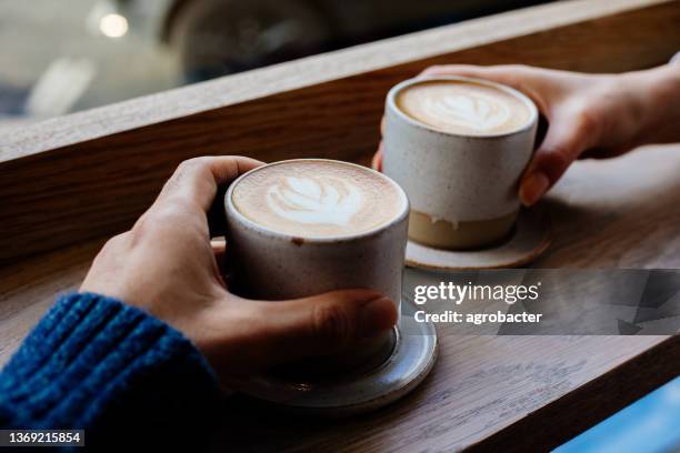 close up woman and man holding cups of coffee on table - coffee shop couple stock pictures, royalty-free photos & images