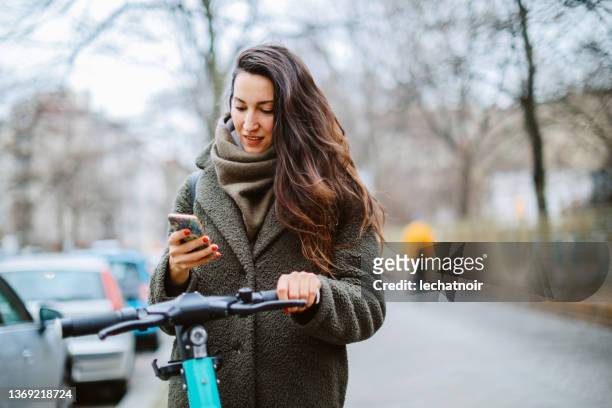 commuter in berlin on electronic scooter checking mobile app - berlin winter stock pictures, royalty-free photos & images