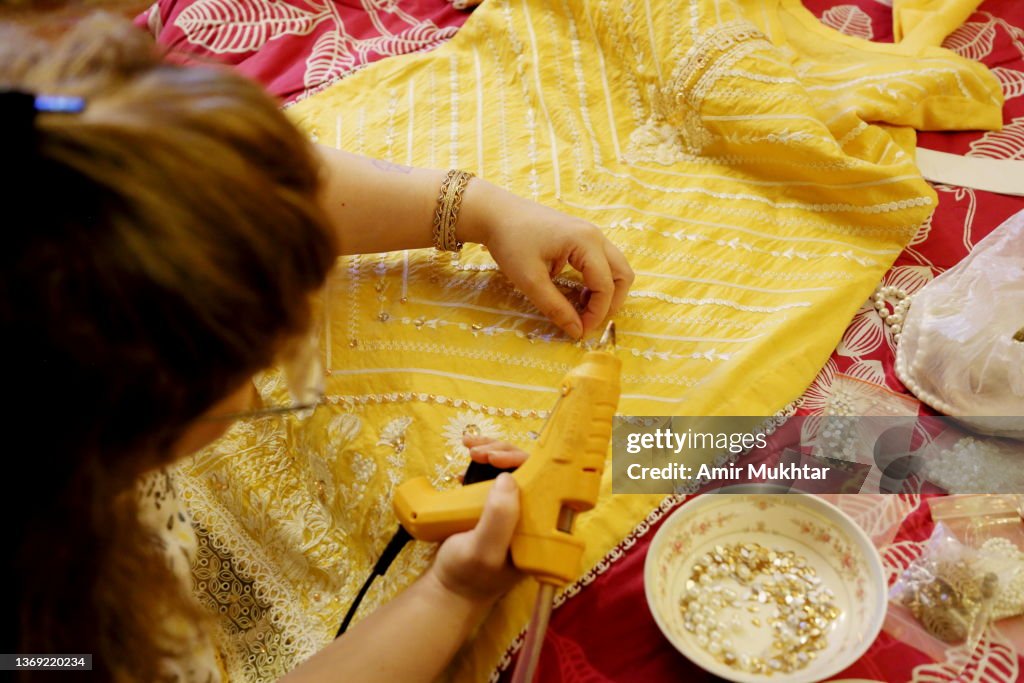 High angle view of a woman pasting beads and pearls on a shirt with glue gun.