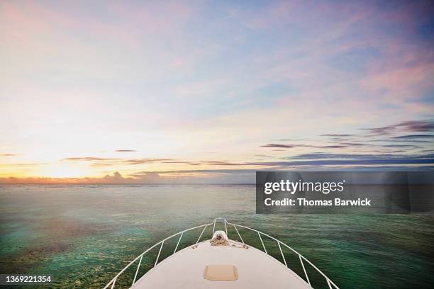 wide shot of bow of sport fishing boat cruising in ocean at sunrise - proas fotografías e imágenes de stock