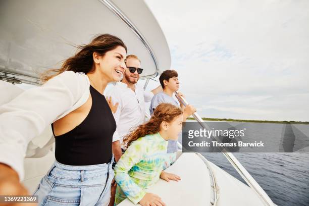 medium shot of smiling family standing on flybridge of boat while cruising in tropical sea - medium group of people foto e immagini stock
