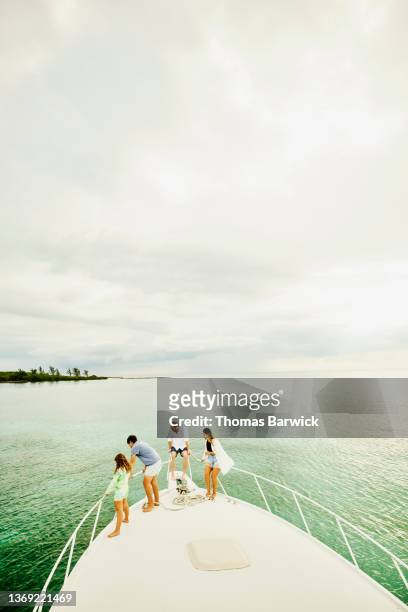 Extreme wide shot of family on bow of boat while on vacation in tropical sea