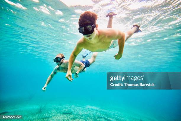 Wide shot underwater view of father and son snorkeling in tropical sea