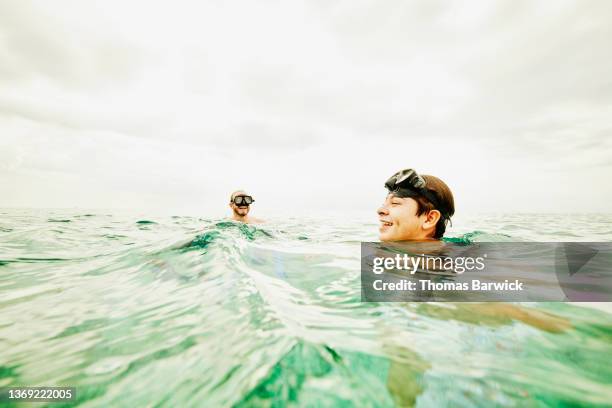 Wide shot view from water of smiling father and son snorkeling in tropical sea