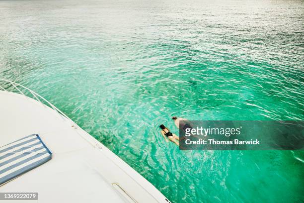 Wide shot high angle view of couple snorkeling near boat in tropical sea