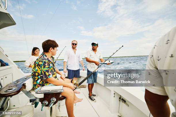 wide shot of smiling family on sport fishing boat while on vacation - father son admiration stock pictures, royalty-free photos & images