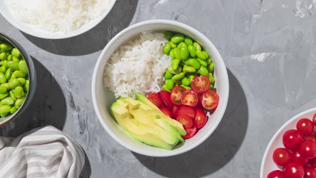 Hawaiian poke bowl with shrimps, rice and vegetables. Healthy bowl with prawns, rice, edamame beans, tomato and avocado. Stop motion animation.