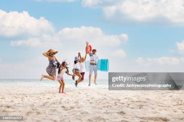 happy asian family jumping together on the beach in holiday. silhouette of the family holding hands enjoying the sunset on the beach.happy family travel and vacations concept. - travel family imagens e fotografias de stock
