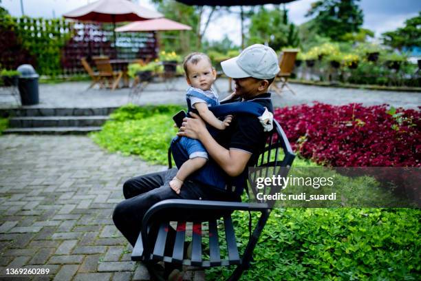 man playing with her baby on the public park - boy sitting stock pictures, royalty-free photos & images