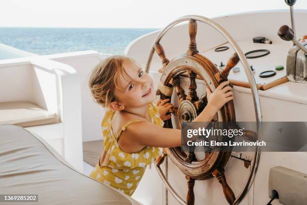 little girl driving a yacht. the concept of vacation and travel with children. - hand steering wheel stock pictures, royalty-free photos & images
