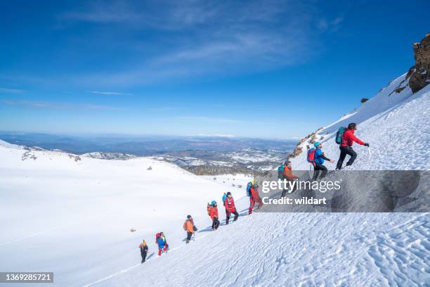 mountain alpine climbing team is walking in a row in high altitude mountain peak in winter - climbing a mountain stock pictures, royalty-free photos & images