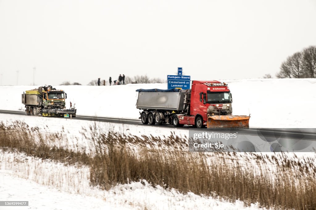 Camión de vehículos de servicio de invierno con arado de nieve despejando las carreteras de nieve y hielo