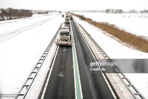 winter service vehicle truck with snow plow clearing the roads of snow and ice - winterdienst stockfoto's en -beelden