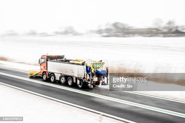 winter service vehicle truck with snow plow clearing the roads of snow and ice - winterdienst stockfoto's en -beelden