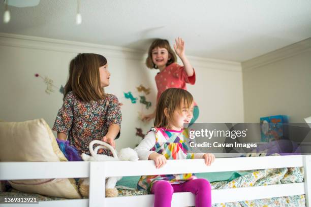 girls, sisters playing on top bunk of bed in their room. - bunk beds for 3 stock pictures, royalty-free photos & images