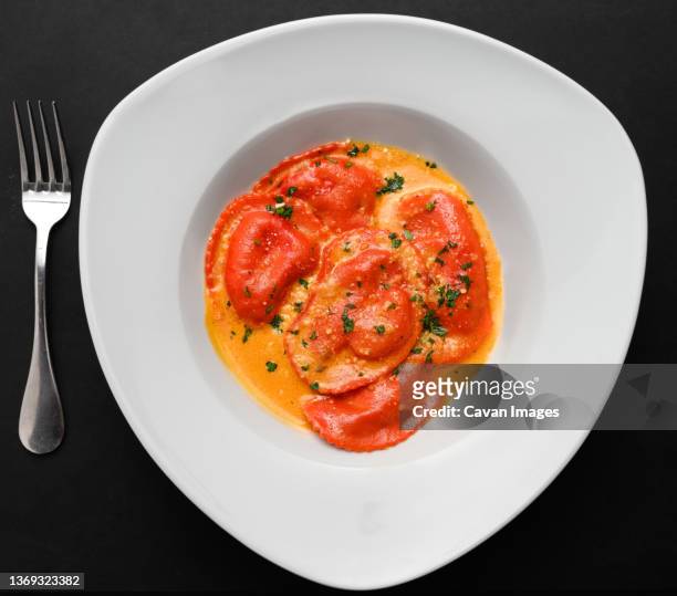 red ravioli in a white plate over a black background - ricotta cheese stock pictures, royalty-free photos & images