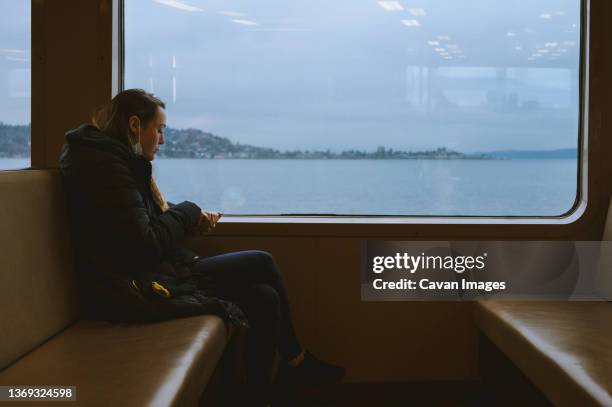 female sitting on ferry eating a snack with a window view - commuter ferry stock pictures, royalty-free photos & images