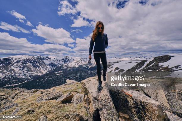 young woman hiking in a melted snow field, summertime rocky mountains - rocky mountain national park stock pictures, royalty-free photos & images