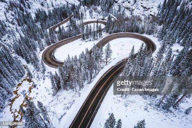 mountain road snakes through pine trees in winter, colorado - silverton colorado stock pictures, royalty-free photos & images