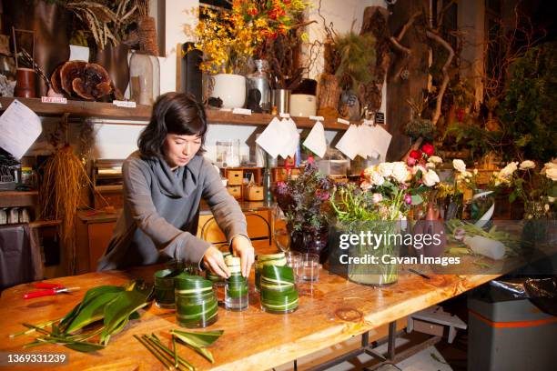 female florist lining vases with leaves for flower bouquets, nyc - hurricane sally fotografías e imágenes de stock