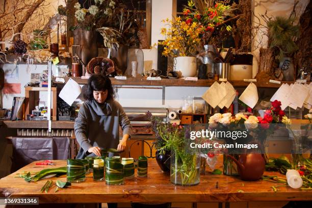 female florist lining vases with leaves for flower bouquets, nyc - hurricane sally fotografías e imágenes de stock