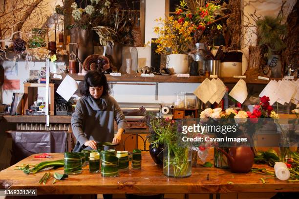 female florist lining vases with leaves for flower bouquets, nyc - hurricane sally - fotografias e filmes do acervo