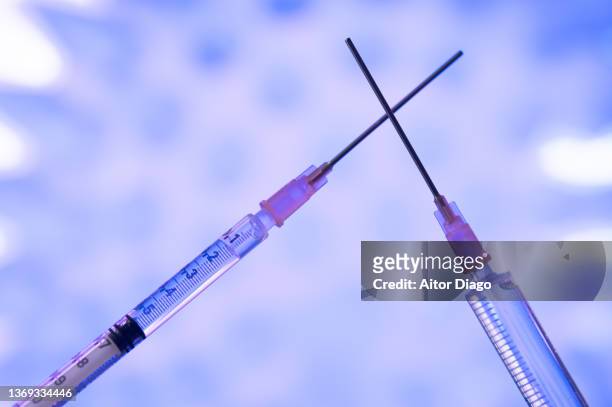 two syringes with a vaccine against the  covid-19 for different covid-19  mutations as omicron or delta. a coronavirus in the background. - booster dose stock pictures, royalty-free photos & images