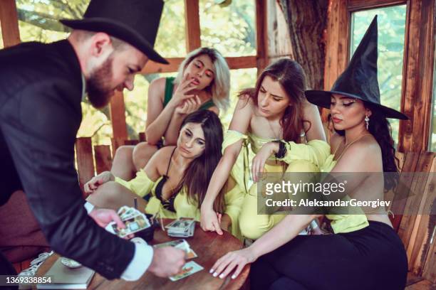 male magician making females believe in his tarot reading skills - witch hat stock pictures, royalty-free photos & images