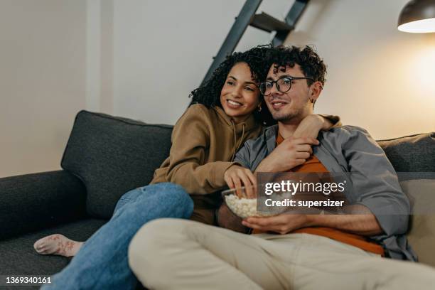 young couple relaxing at home watching tv - couple tv bildbanksfoton och bilder