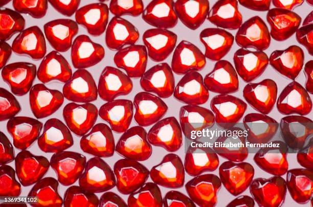 red heart gems on pink background - edelsteinimitation stock-fotos und bilder