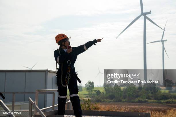 electric engineer wearing full personal protective equipment working at wind turbine farm. - air quality stock pictures, royalty-free photos & images