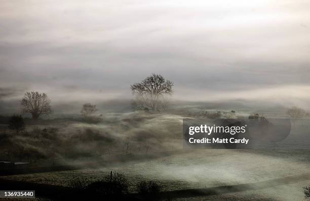 Mist and fog rolls across agricultural fields as the sun rises over the Somerset Levels on January 13, 2012 in Glastonbury, England. After...